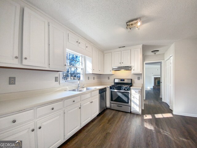 kitchen with white cabinets, appliances with stainless steel finishes, sink, a textured ceiling, and dark hardwood / wood-style floors