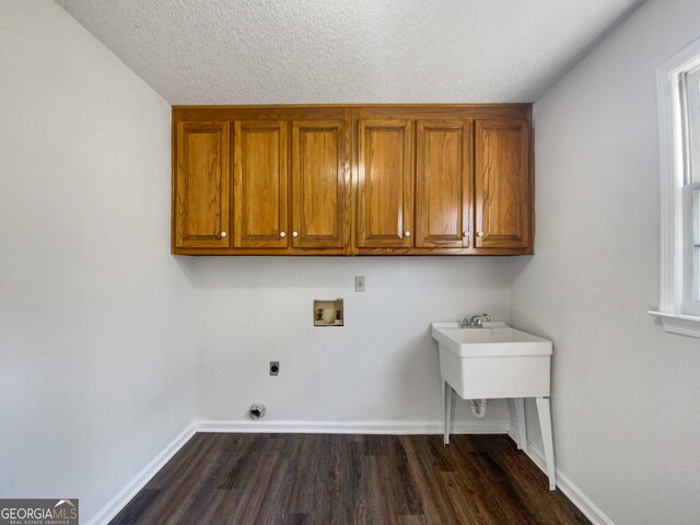 laundry area featuring dark wood-type flooring, hookup for a washing machine, hookup for an electric dryer, a textured ceiling, and cabinets