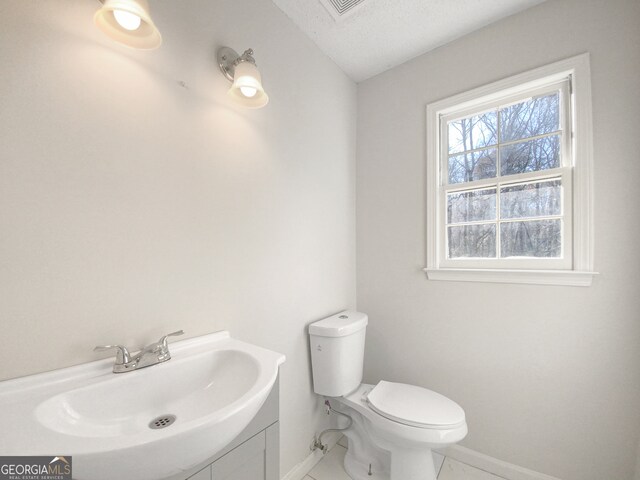 bathroom featuring tile flooring, a textured ceiling, toilet, and vanity