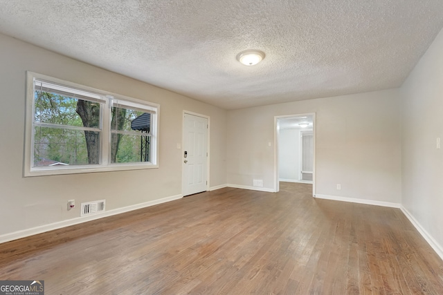 spare room featuring a textured ceiling and dark hardwood / wood-style flooring