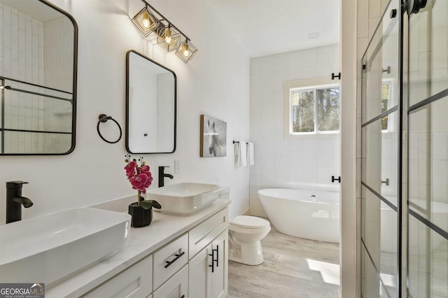 bathroom featuring hardwood / wood-style floors, vanity, toilet, and a bath