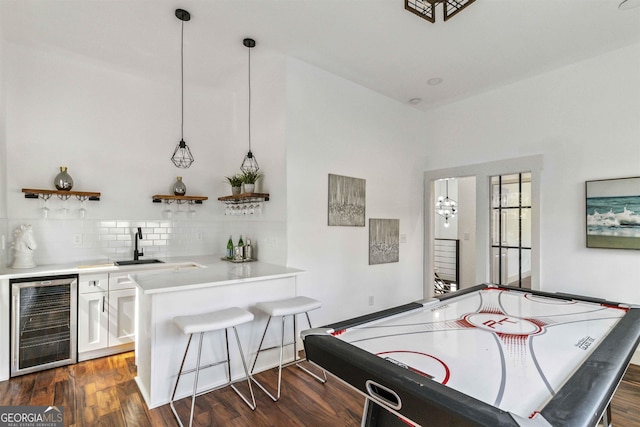 game room with dark hardwood / wood-style flooring, beverage cooler, and wet bar