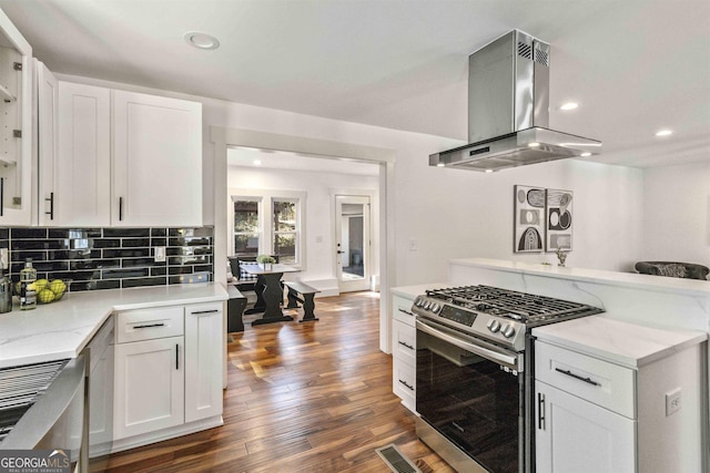 kitchen with island exhaust hood, white cabinets, and stainless steel gas range oven