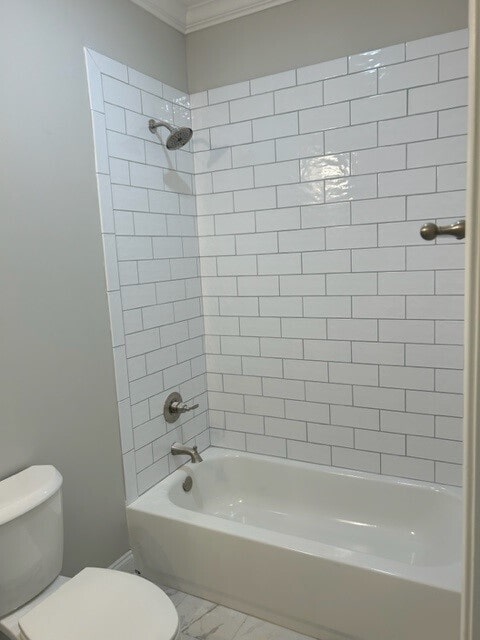 bathroom with ornamental molding, tile flooring, toilet, and tiled shower / bath