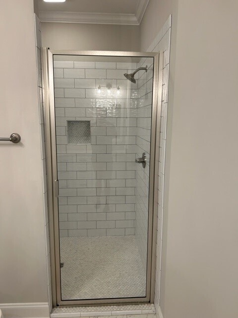 bathroom with a shower with door and ornamental molding