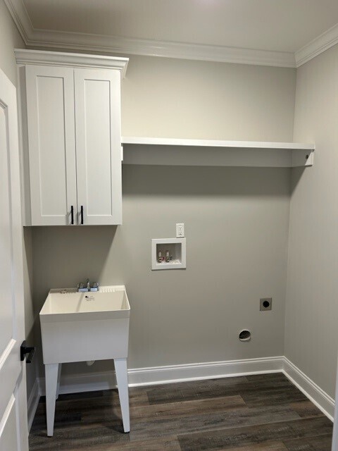 washroom featuring dark wood-type flooring, cabinets, electric dryer hookup, hookup for a washing machine, and crown molding