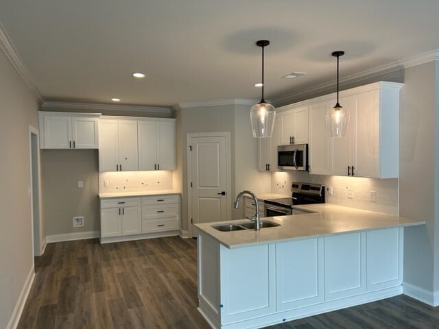 kitchen featuring appliances with stainless steel finishes, white cabinetry, pendant lighting, backsplash, and sink