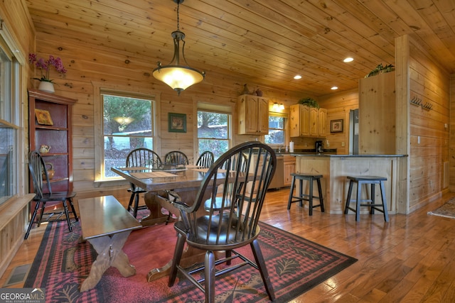 dining room with wooden ceiling, light hardwood / wood-style floors, and wood walls