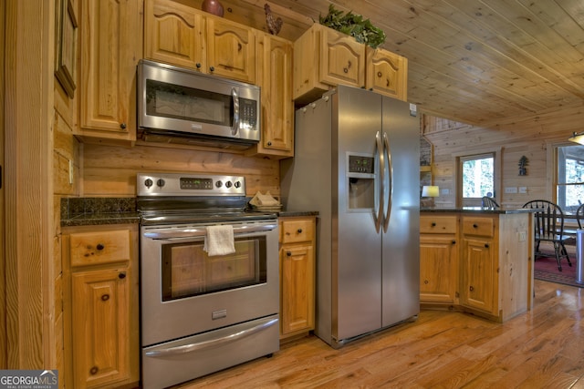 kitchen with wooden walls, appliances with stainless steel finishes, light hardwood / wood-style flooring, and kitchen peninsula