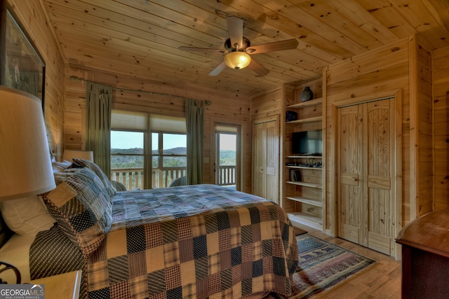 bedroom with wooden walls, wooden ceiling, light wood-type flooring, and ceiling fan