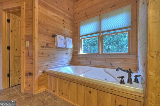 bathroom with wooden walls, tile patterned floors, plenty of natural light, and a washtub