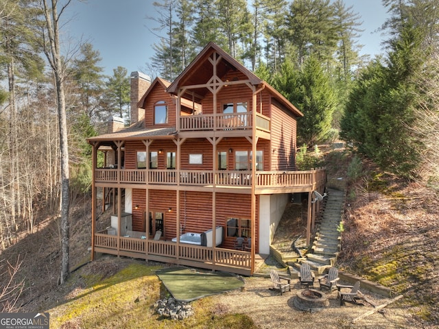 rear view of house with a wooden deck and an outdoor fire pit