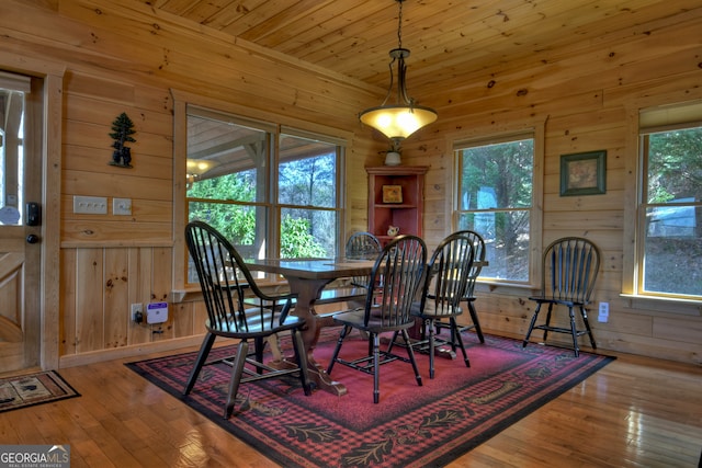 dining area featuring hardwood / wood-style floors, wood ceiling, and wooden walls