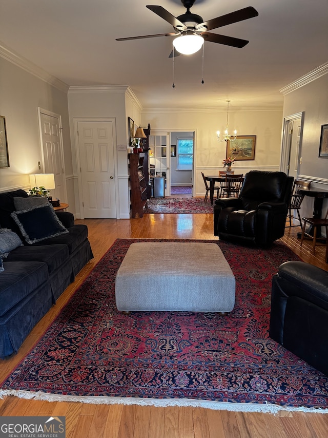 living room with crown molding, hardwood / wood-style flooring, and ceiling fan with notable chandelier