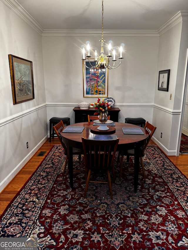 dining space featuring crown molding, an inviting chandelier, and hardwood / wood-style floors