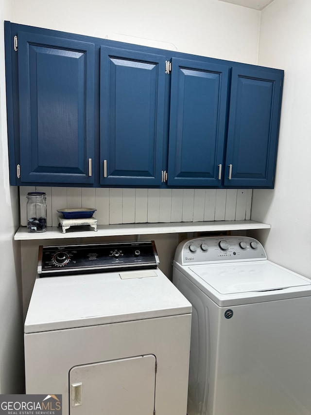 clothes washing area with separate washer and dryer and cabinets