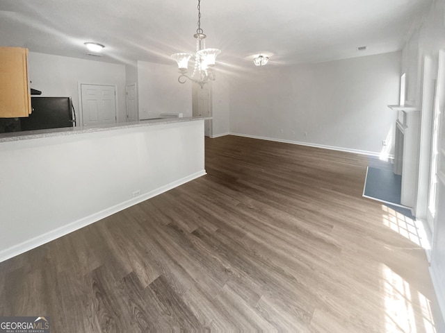 unfurnished living room featuring an inviting chandelier and dark wood-type flooring