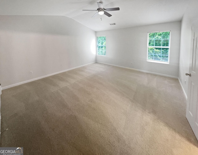 spare room with ceiling fan, light carpet, and vaulted ceiling