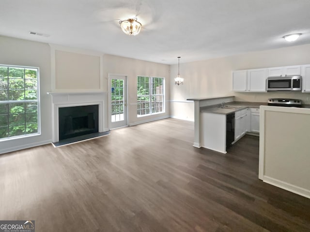 kitchen featuring visible vents, a peninsula, stainless steel appliances, white cabinetry, and dark wood-type flooring