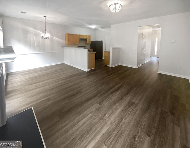 unfurnished living room with lofted ceiling, dark hardwood / wood-style floors, and an inviting chandelier