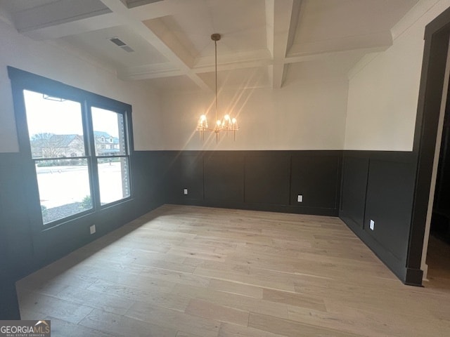 spare room featuring a notable chandelier, light hardwood / wood-style flooring, coffered ceiling, and beamed ceiling