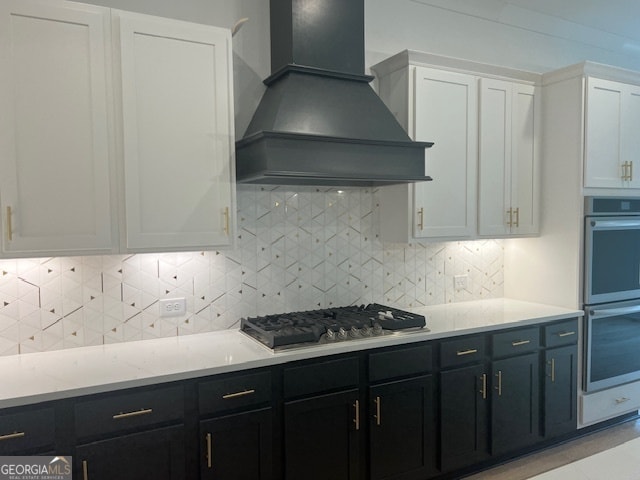 kitchen featuring custom range hood, stainless steel appliances, backsplash, and white cabinets