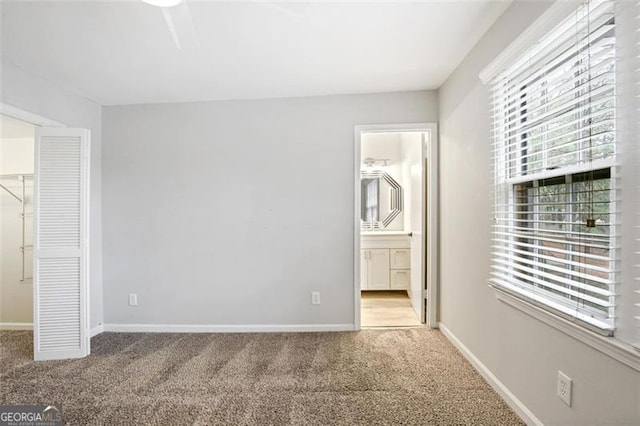 unfurnished bedroom featuring a closet, multiple windows, a walk in closet, and ensuite bath