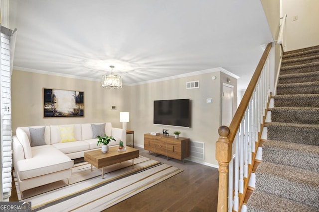 living room with dark wood-type flooring, ornamental molding, and a notable chandelier