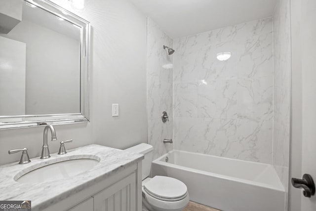 full bathroom featuring tiled shower / bath, vanity, and toilet