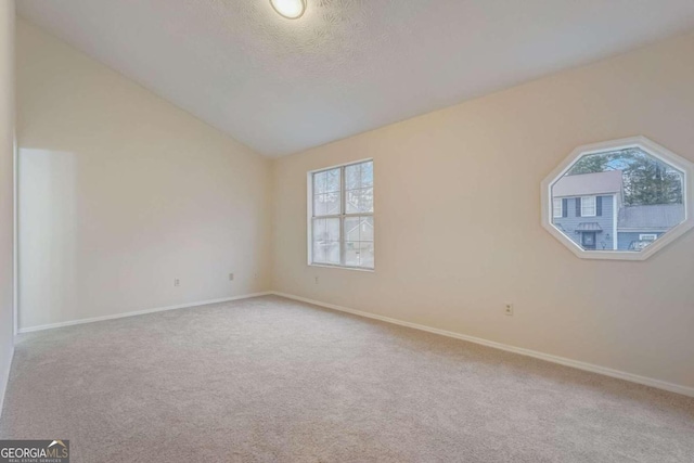 carpeted spare room featuring vaulted ceiling