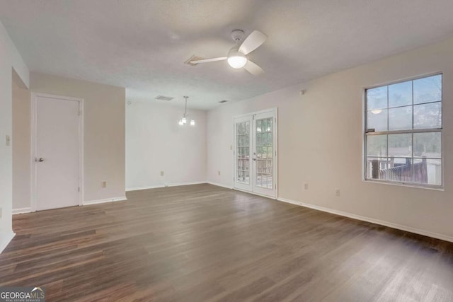 empty room with dark wood-type flooring and ceiling fan with notable chandelier