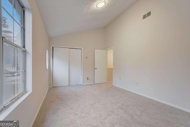 unfurnished bedroom with a closet, light carpet, and high vaulted ceiling