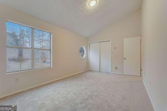 carpeted spare room with lofted ceiling