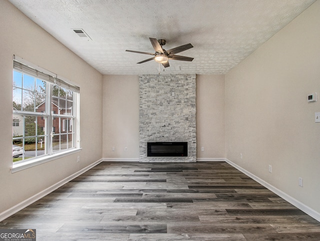 unfurnished living room with dark hardwood / wood-style flooring, ceiling fan, a textured ceiling, and a fireplace