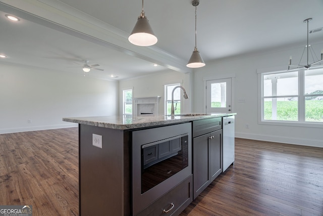 kitchen with ceiling fan, pendant lighting, white dishwasher, an island with sink, and black microwave