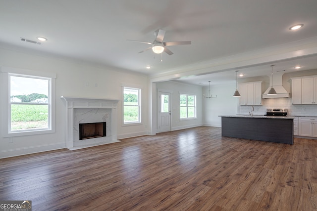 unfurnished living room with ceiling fan, dark hardwood / wood-style floors, a high end fireplace, and ornamental molding