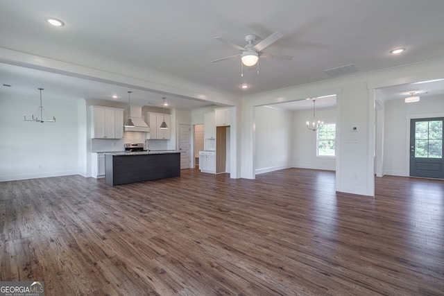 unfurnished living room with a wealth of natural light, ceiling fan with notable chandelier, and dark hardwood / wood-style flooring