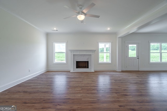 unfurnished living room with ceiling fan, plenty of natural light, crown molding, and a premium fireplace