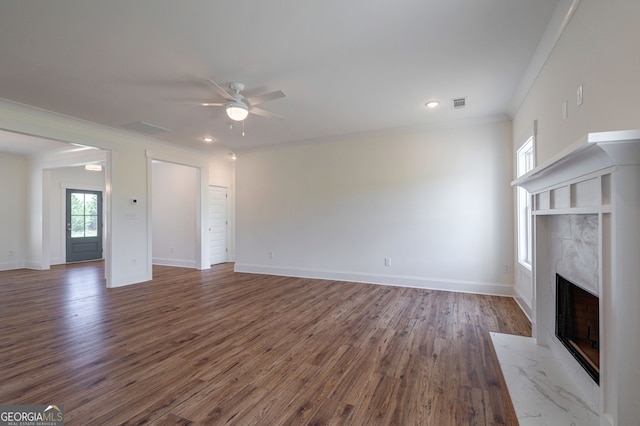 unfurnished living room featuring ceiling fan, dark hardwood / wood-style flooring, crown molding, and a tiled fireplace