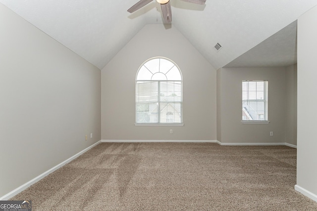 carpeted spare room featuring vaulted ceiling and ceiling fan