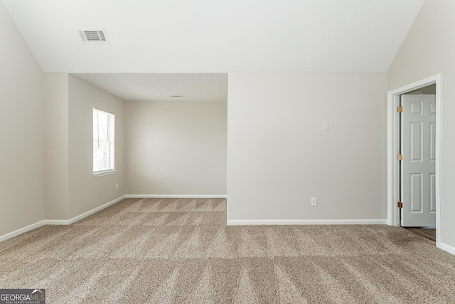 carpeted empty room with lofted ceiling