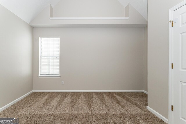 carpeted spare room featuring lofted ceiling