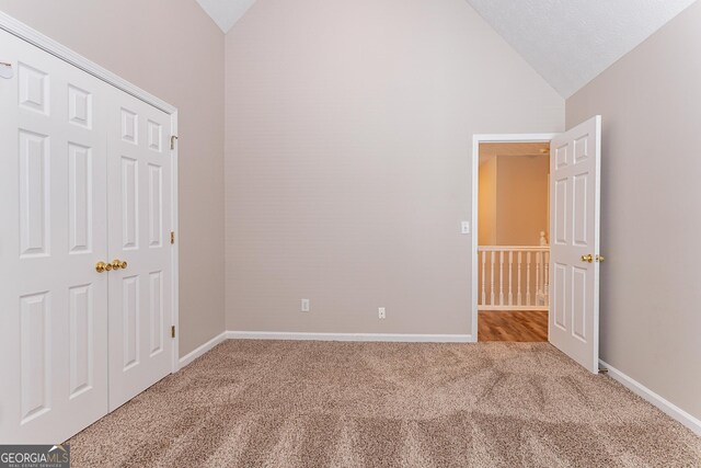 unfurnished bedroom featuring high vaulted ceiling and carpet