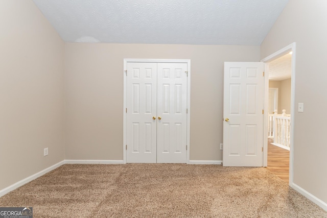 unfurnished bedroom featuring carpet flooring, a textured ceiling, and a closet