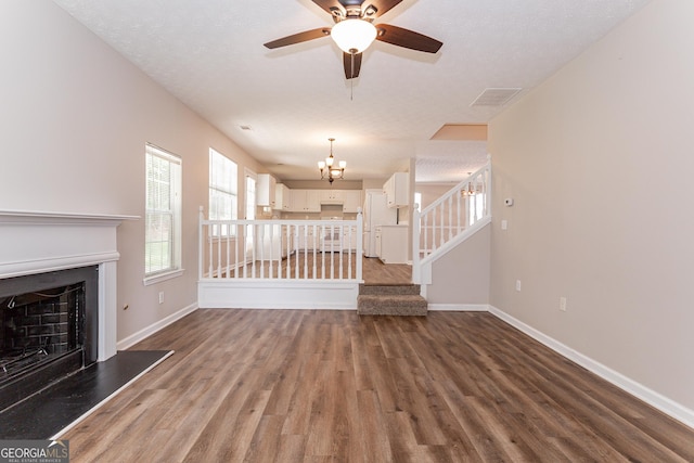 unfurnished living room with hardwood / wood-style flooring, ceiling fan with notable chandelier, and a textured ceiling