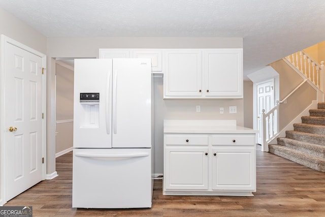 kitchen with white cabinetry, dark hardwood / wood-style floors, white refrigerator with ice dispenser, and a textured ceiling