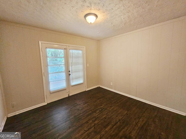 unfurnished room featuring dark wood-type flooring and a textured ceiling