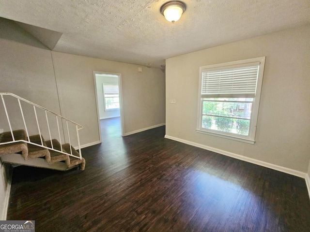 empty room with a textured ceiling and dark wood-type flooring