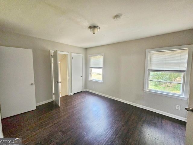 unfurnished bedroom with dark wood-type flooring and multiple windows