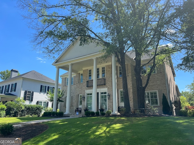 neoclassical / greek revival house featuring a front lawn and a balcony